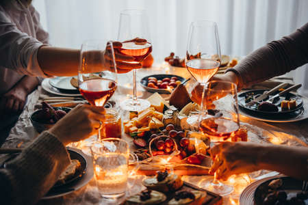 Friends having a dinner party with different kinds of appetizers and rose wine.の写真素材