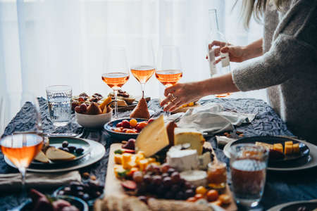 Friends having a dinner party with different kinds of appetizers and rose wine.の写真素材