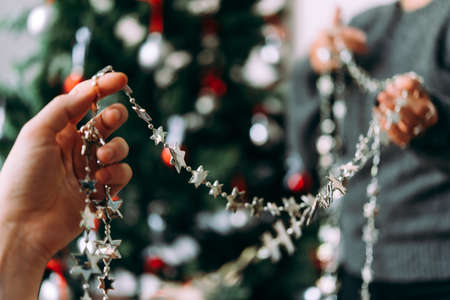 Friends or family decorating a Christmas tree. Christmas and New Year celebration concept. Selective focusの写真素材