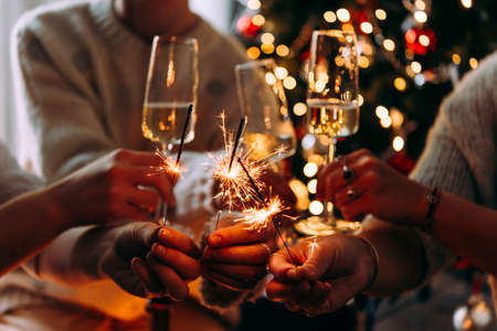 Friends celebrating Christmas or New Year eve party with Bengal lights and champagne.の写真素材