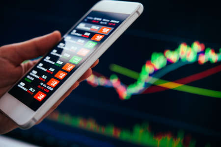 A trader or a financial analyst checking the recent stock exchange trends using the smartphone.の写真素材