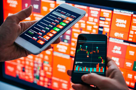 Traders or financial analysts checking the recent stock exchange trends using their smartphones. Selective focusの写真素材