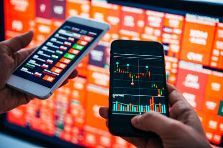 Traders or financial analysts checking the recent stock exchange trends using their smartphones.の写真素材