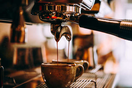 Coffee made in professional espresso machine pouring into a cupの写真素材