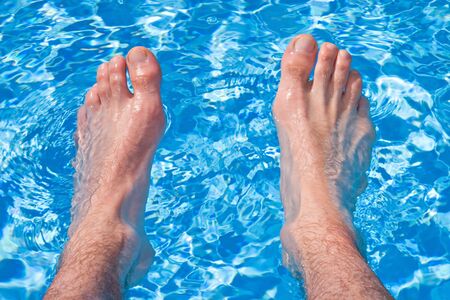 Holliday Relaxation on Pool - Men feet in transparent water