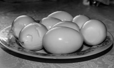 BW photo of several eggs, peeled out of shells, lying on a plate