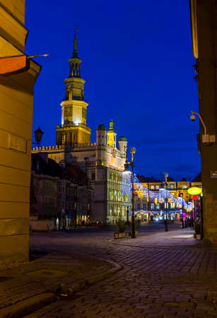 Night photo of an old town square and city hall in Poznan, Poland from one of cobbled, neighbouring streetsの写真素材