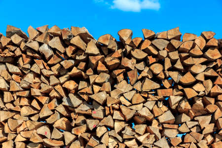 Logs of wood  piled together in lumber-mill with blue sky in the top of the pictureの写真素材