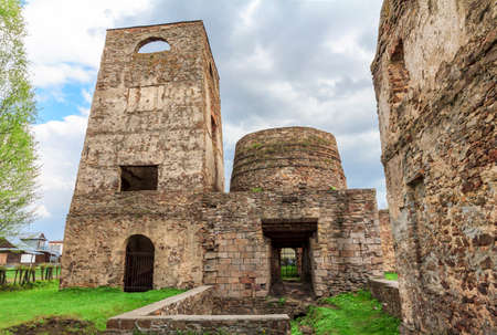 Fragment of  the ruins of an old ironworks with a chimney in the centreの写真素材