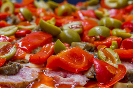 surface of pizza prepared for baking with raw slices of olives, sausage and paprikaの写真素材