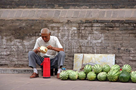 Pingyao, China - July 26, 2009  A watermelon street seller eats his lunch on July 26, 2009  Pingyao ancient town is one of the greatest attractions of Shanxi province のeditorial素材