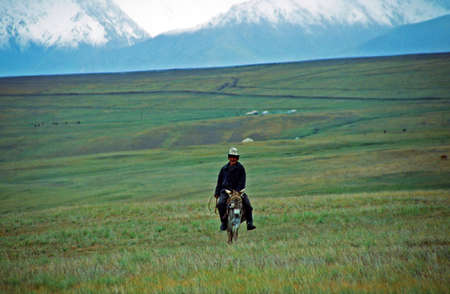 Allay Valley, Kyrgyzstan - circa August 2002  A lone Kyrgyz rides the donkey in the Alay valley with Pamir mountains in background on circa August 2002  のeditorial素材
