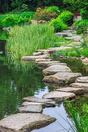 Footbridge across the pond made of stones  This element of a japanese garden is called ishibashi の写真素材