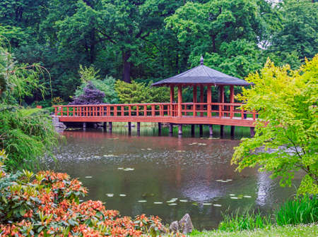 Red bridge with a view pavilion - yumedono bashi, characteristic element of classic japanese gardens, pond and colorful plantsの写真素材