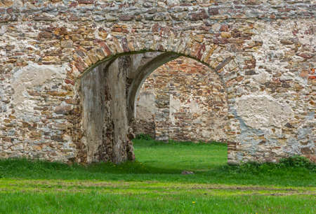 Fragment of  old ruins built with stone bricks with a gate in the center giving view across the ruinsの写真素材