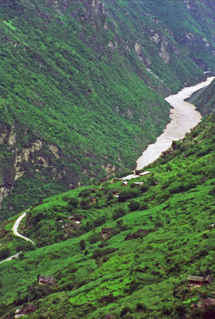 vertical vintage style photo of  leaping tiger gorge, yunnan, china -village on mountain side and river winding in the canyon enshrouded with mistの写真素材