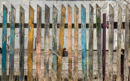 Fragment of an old crumbling wooden fence composed of planks of different colorsの写真素材