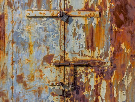 corroded bolts and padlocks on the door of a metal hutの写真素材