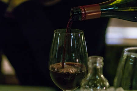 Waiter pouring red wine in a glass.