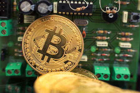 Bitcoin gold coin on computer circuit board microchips. Electronic cryptocurrency.の写真素材