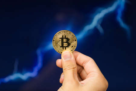 Man holding Bitcoin gold coin in front of lightning network concept background