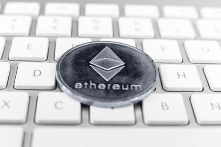 Ethereum coin lying on white computer keyboardの写真素材
