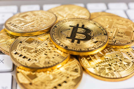 Stack of bitcoins lying on computer keyboardの写真素材