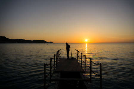 Silhouette of a man getting ready for swimming in seaside on sunsetの写真素材