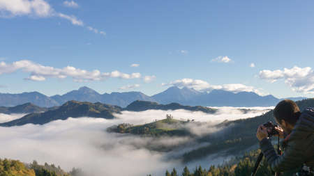 man on wheelchair taking photos of beautiful landscape in a foggy morning, St. Thomas Sloveniaの写真素材