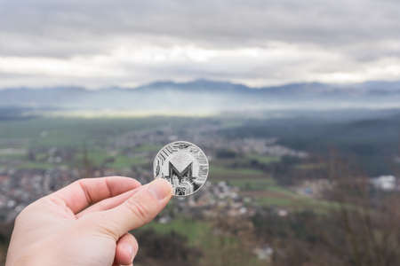 Monero silver coin, Hand hold Monero above the cityの写真素材
