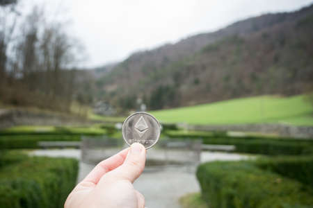 Ethereum silver coin, Hand hold ethereum in the park and natural backgroundの写真素材