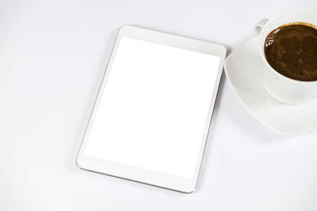 Computer tablet with white empty screen next to coffee. The tablet is on the white table. View from the top. Close-up.の写真素材