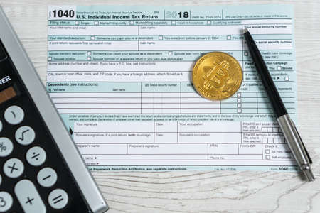 The pen, bitcoins and calculator on the tax form 1040 U.S. Individual Income Tax Return. The time to pay taxesの写真素材