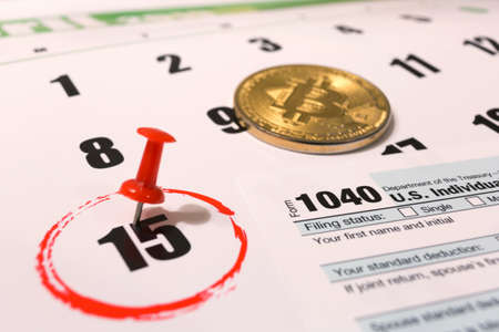Bitcoin and 2019 calendar with 1040 income tax form for 2018 showing tax day for filing on April 15の写真素材