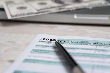 US tax form 1040 with pen and dollar bills. tax form law document usa white business conceptの写真素材