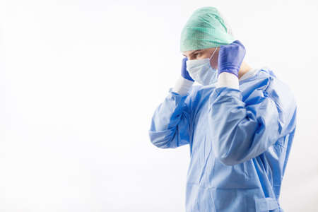 Surgeon doctor in sterile gloves preparing for operation in hospital. He is wearing surgical cap and blue gownの写真素材