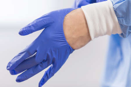 Surgeon doctor in sterile gloves preparing for operation in hospital. He is wearing surgical cap and...