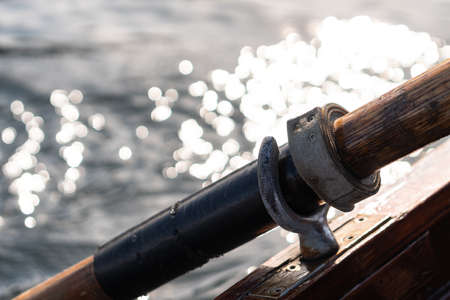 Closeup photo of wooden paddle attached to boat used for rowing in the water, lake Bled on a sunny dayの写真素材