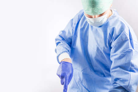 Surgeon doctor in sterile gloves preparing for operation in hospital. He is wearing surgical cap and blue gownの写真素材