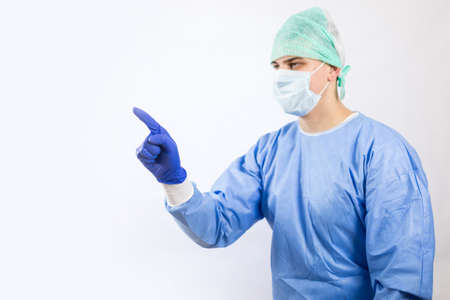 Surgeon doctor in sterile gloves preparing for operation in hospital. He is wearing surgical cap and blue gownの写真素材