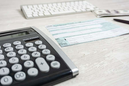 US tax form next to computer keyboard, calculator and tax form 1040. tax form us business income office hand fill conceptの写真素材