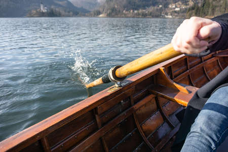 Young woman using paddle on a wooden boat with island Bled behind it - Lake Bled Slovenia rowing on wooden boatsの写真素材
