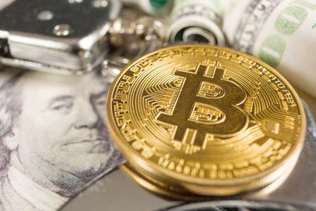 Golden Bitcoins Cryptocurrency with Handcuffs on Dollar bills. Digital crime, arrest or hacking concept.の写真素材