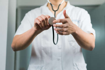 Bright close up of male doctor in uniform with stethoscope. Listening and holding stethoscope. Copy spaceの写真素材