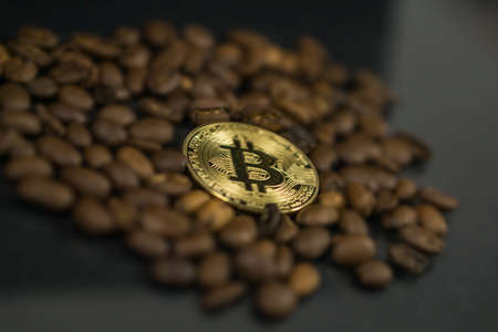 Bitcoin cryptocurrency coin as payment currency surrounded with coffee beansの写真素材