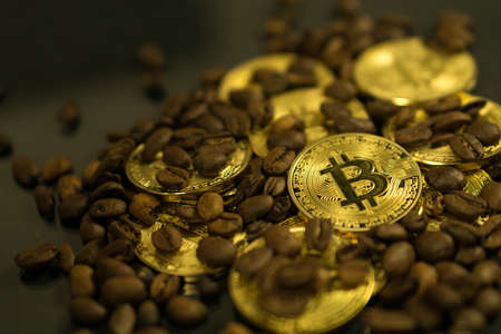Bitcoin cryptocurrency coin as payment currency surrounded with coffee beansの写真素材
