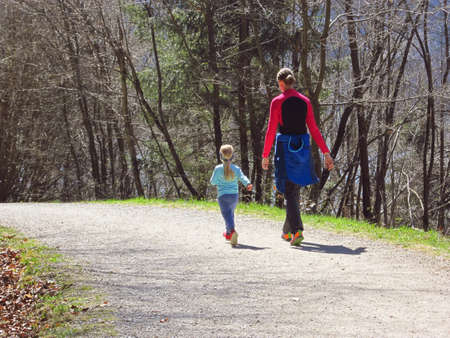 Mother with little girl daughter hiking and having fun and beeing happy together. Family trip by the lake in a forest at spring.の写真素材