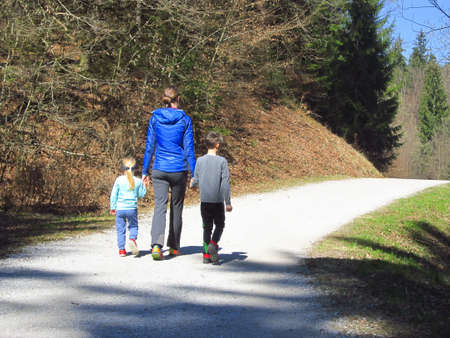 Mother with son and daughter hiking and having fun and beeing happy together and holding hands. Family trip in a forest at spring.の写真素材