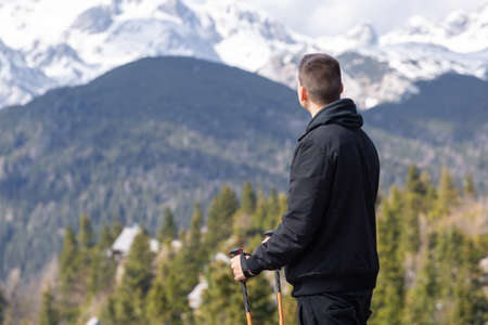 Casual and active healthy man hiking in Alpine mountains with trekking poles