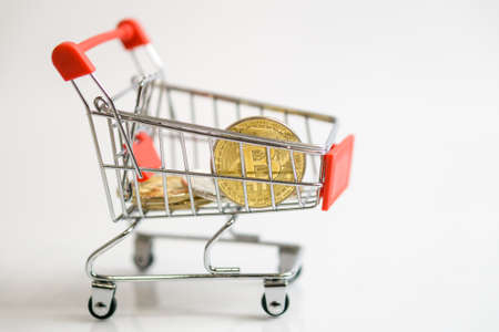 Shopping trolley cart with Coins bitcoin, buying goods for crypto currency.の写真素材